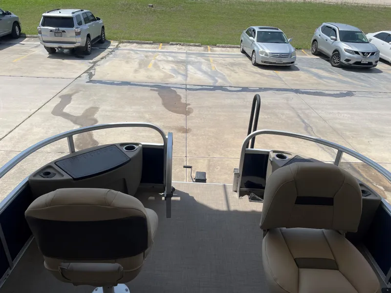 Slide: The Image of 2025 Sun Tracker Bass Buggy 18 DLX pontoon boat interior with seating, parked in a lot. - 4