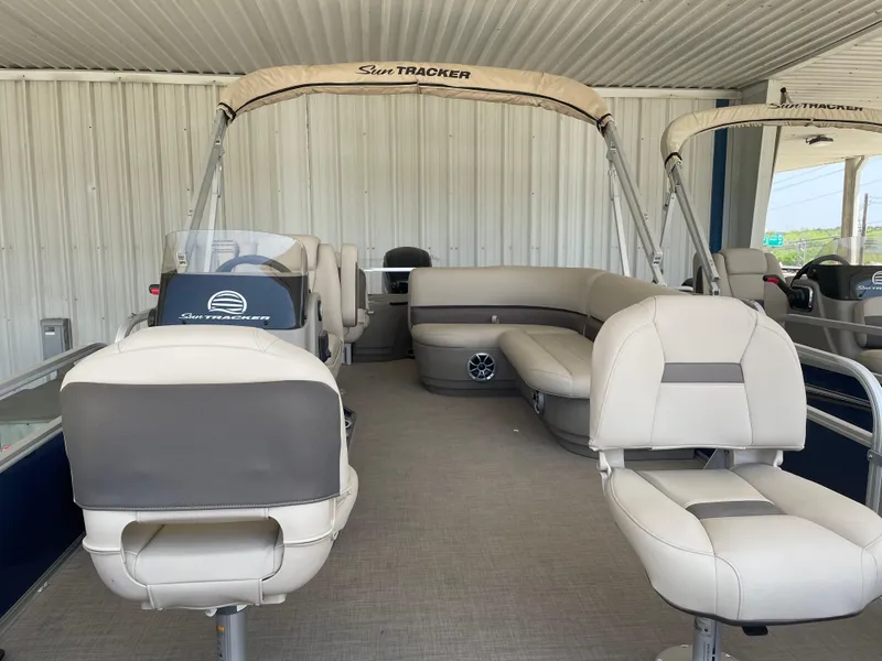 Slide: The Image of 2025 Sun Tracker Bass Buggy 18 DLX pontoon boat with beige seating and canopy. - 5