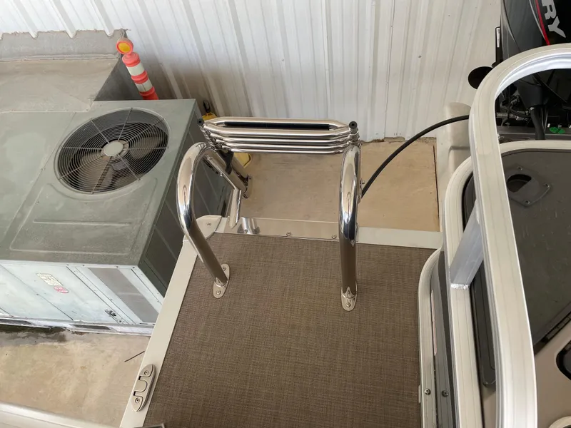 Slide: The Image of 2025 Sun Tracker Bass Buggy 18 DLX boat ladder and deck area in a storage facility. - 9