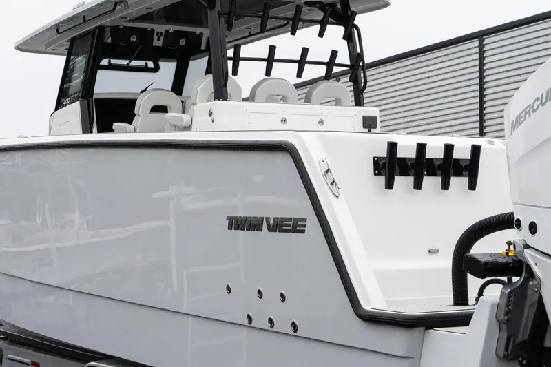 Slide: The Image of 2025 Twin Vee 400 GFX CC boat, sleek design, white exterior, modern seating, and fishing rod holders. - 10