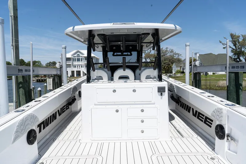 Slide: The Image of 2025 Twin Vee 400 GFX CC boat, spacious deck, sleek design, docked near waterfront homes. - 16