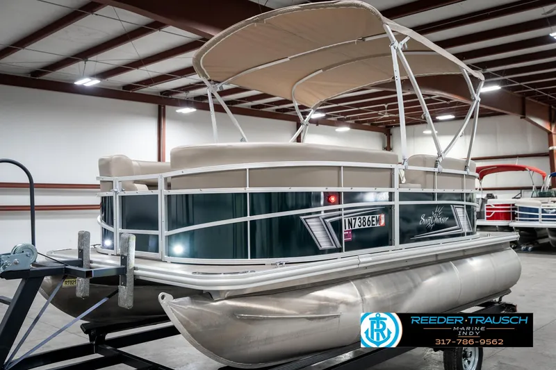Slide: The Image of 2024 SunChaser 16 Vista pontoon boat in a showroom, featuring a beige canopy. - 3