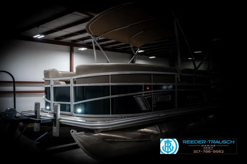Slide: The Image of 2024 SunChaser 16 Vista pontoon boat in a dimly lit indoor setting. - 4