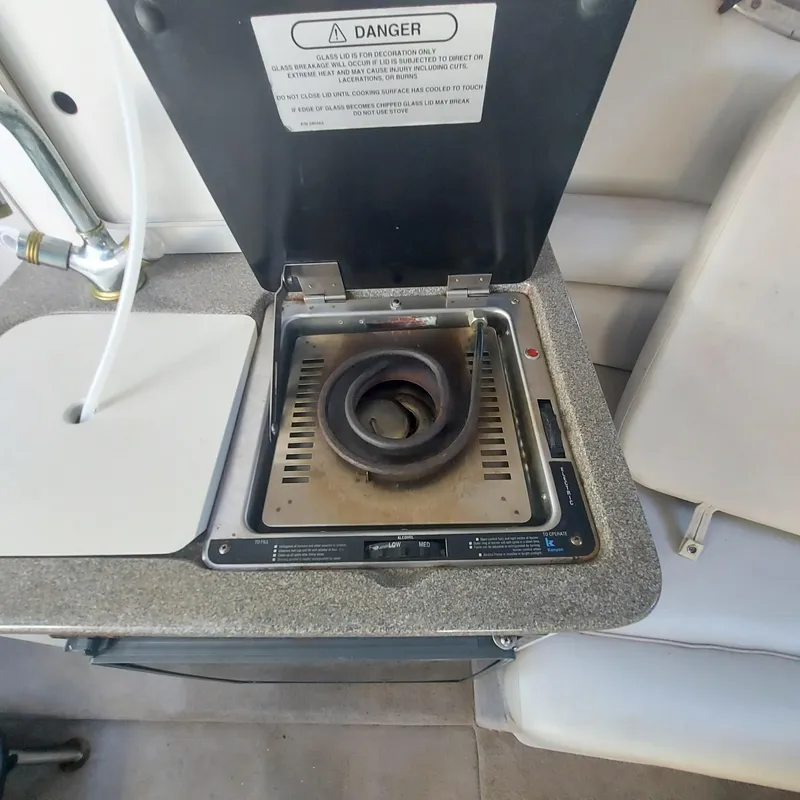 Slide: The Image of Stove on 2000 Crownline 242 CR boat, featuring a single burner and safety warning label. - 13