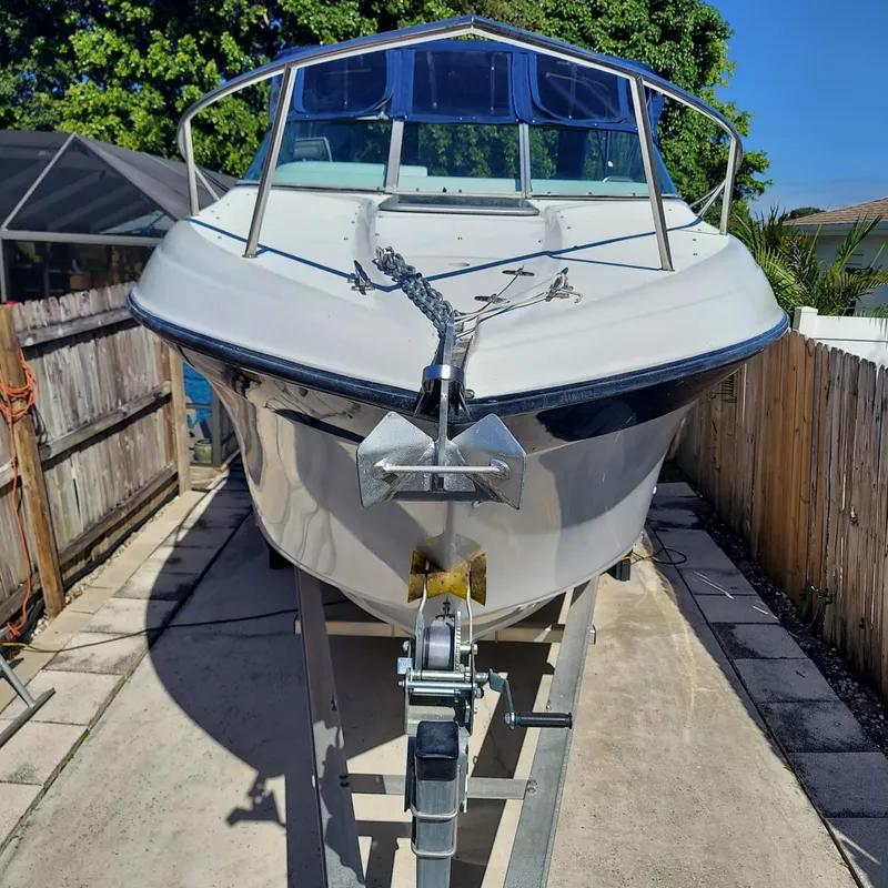 Slide: The Image of 2000 Crownline 242 CR boat on trailer, parked in driveway, sunny day. - 2