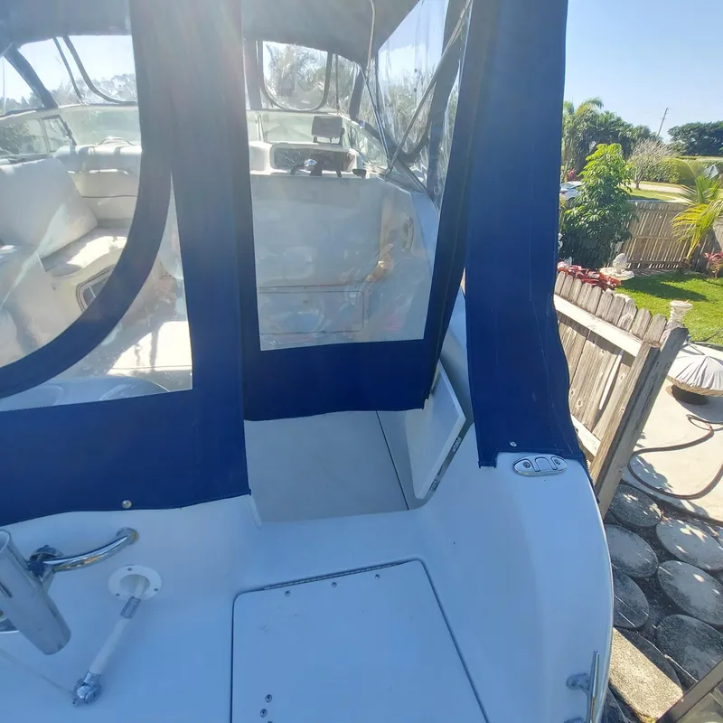 Slide: The Image of 2000 Crownline 242 CR boat with blue canopy, docked outdoors. - 32