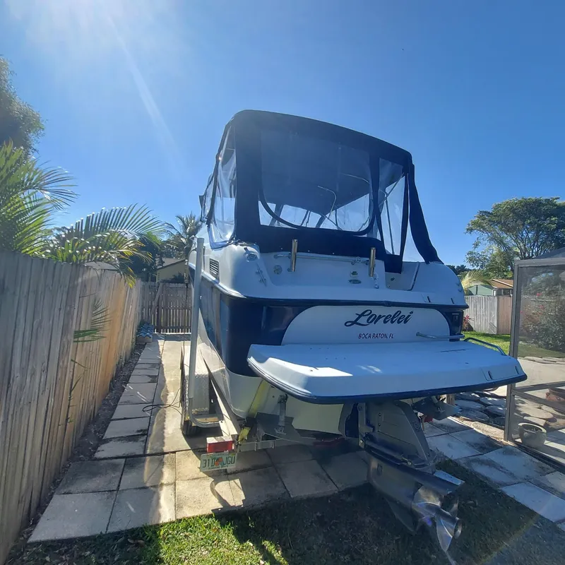 Slide: The Image of 2000 Crownline 242 CR boat parked on a paved driveway under clear blue sky. - 4