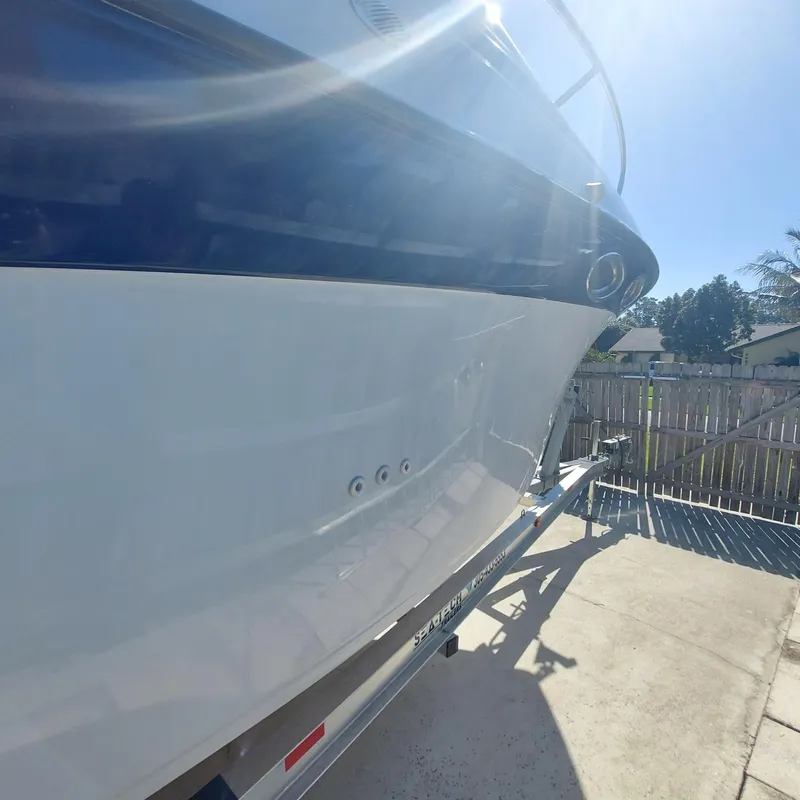 Slide: The Image of 2000 Crownline 242 CR boat on trailer, sunlit, with blue and white hull. - 43