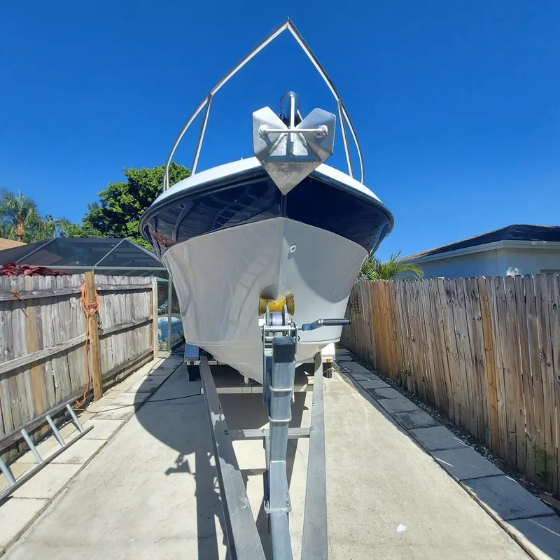 Slide: The Image of 2000 Crownline 242 CR boat on trailer, parked in driveway under clear blue sky. - 45