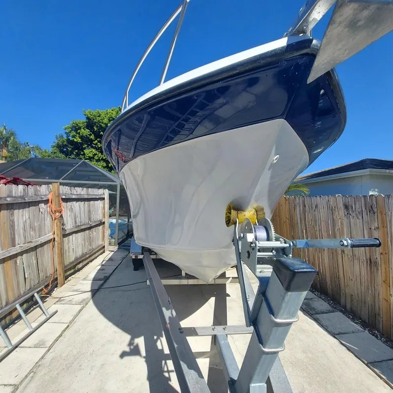 Slide: The Image of 2000 Crownline 242 CR boat on trailer, parked in driveway under clear blue sky. - 46