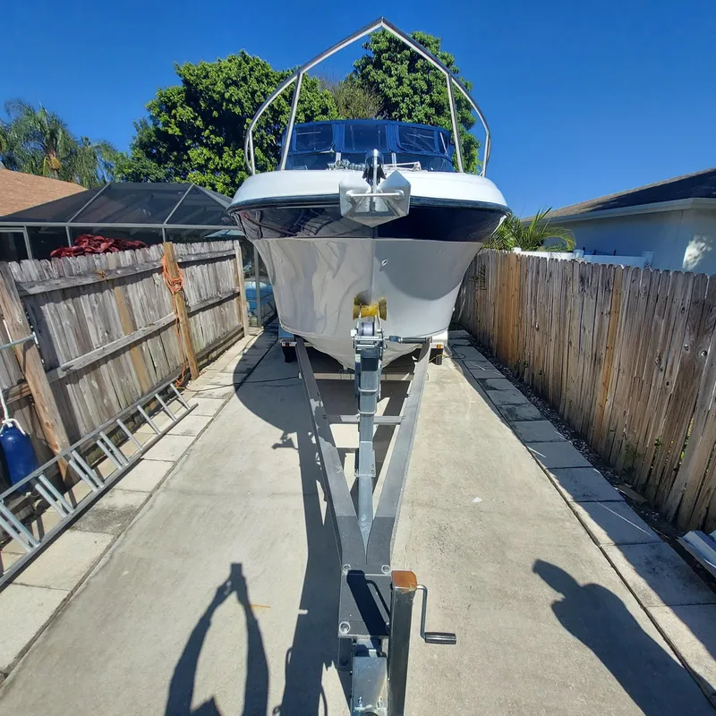 Slide: The Image of 2000 Crownline 242 CR boat on trailer, parked in driveway, sunny day. - 48