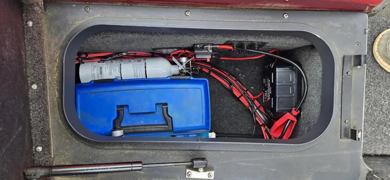 Slide: The Image of 2013 Skeeter ZX20 storage compartment with fire extinguisher, blue toolbox, and battery cables. - 19
