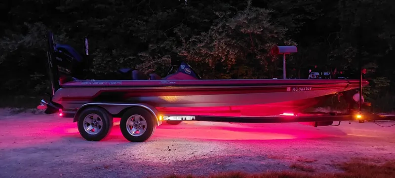 Slide: The Image of 2013 Skeeter ZX20 boat with vibrant pink underglow lights on a trailer at night. - 4
