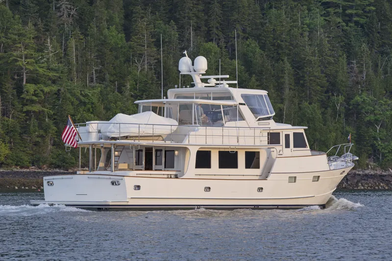 Slide: The Image of Luxury Fleming 78 yacht cruising on a serene lake, surrounded by lush forest, 2027 model. - 1