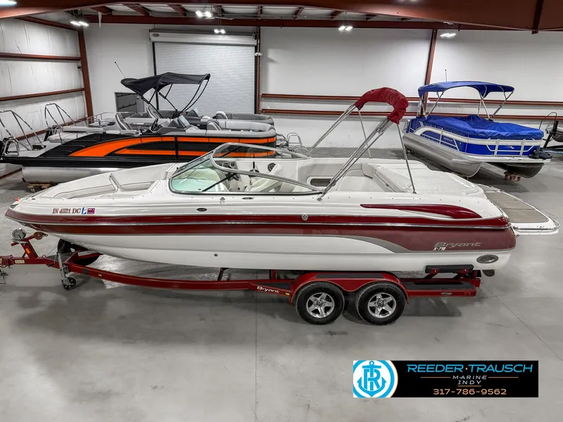 Slide: The Image of 2007 Bryant 240 boat in showroom, red and white design, on trailer, indoor display. - 1