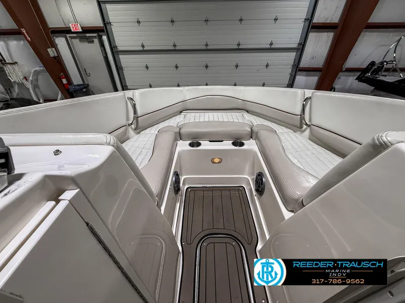 Slide: The Image of 2007 Bryant 240 boat interior with white seating, wood flooring, and cup holders in a garage. - 18