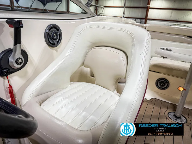 Slide: The Image of White leather seat in a 2007 Bryant 240 boat interior, featuring control panel and wood flooring. - 47