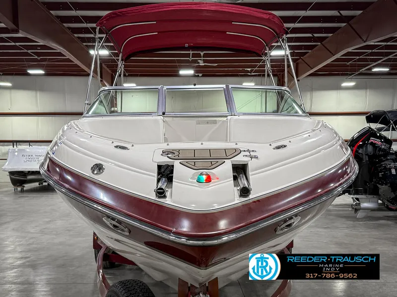 Slide: The Image of Front view of a 2007 Bryant 240 boat with a red canopy in a showroom. - 5