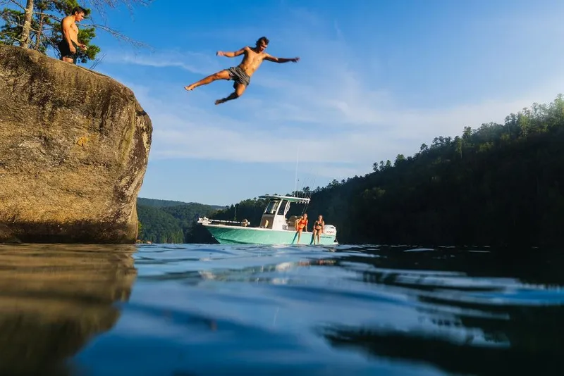 Slide: The Image of Man cliff jumping near 2026 Sportsman Masters 227 Bay Boat on a sunny day. - 45