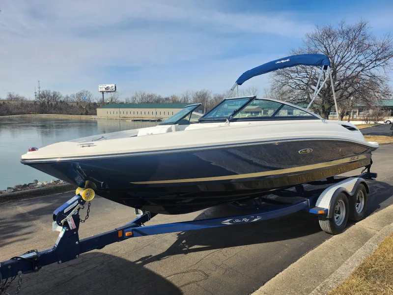 Slide: The Image of 2014 Sea Ray 210 SLX boat on trailer by a lake, blue and white design. - 8