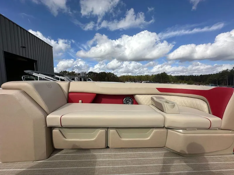 Slide: The Image of 2025 Godfrey SWEETWATER 2286 SB boat interior with beige and red seating under a blue sky. - 6
