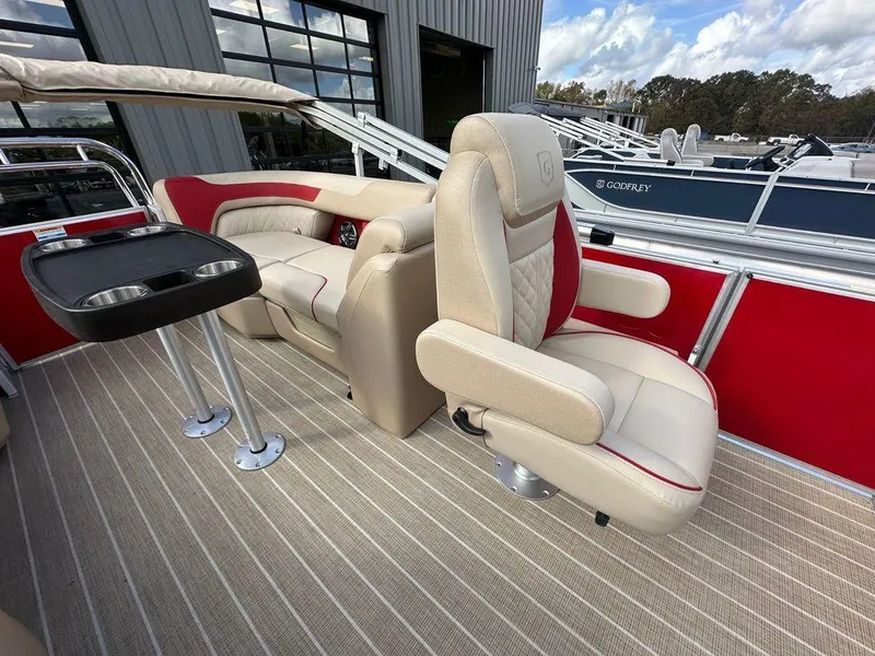 Slide: The Image of 2025 Godfrey SWEETWATER 2286 SB boat interior with beige seating and red accents. - 8
