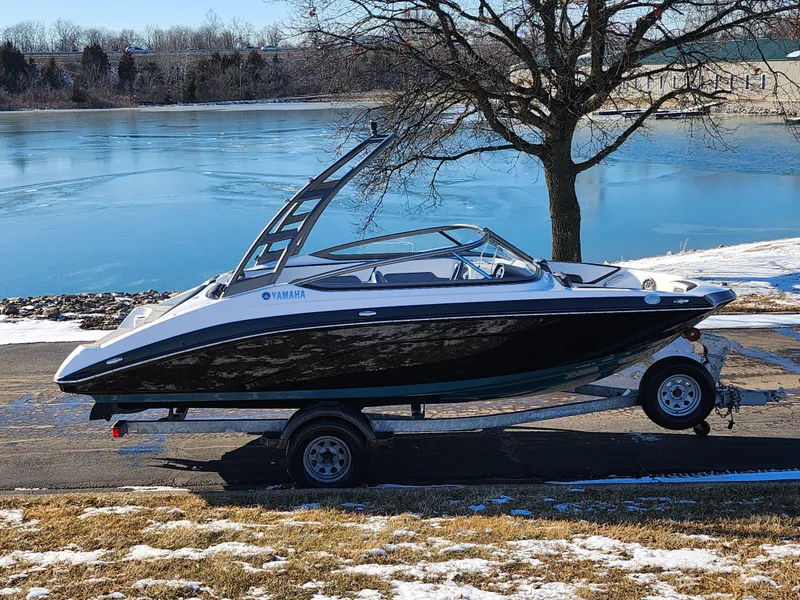 The Image of 2021 Yamaha Boats AR195 on trailer by a serene lake in winter. - 0