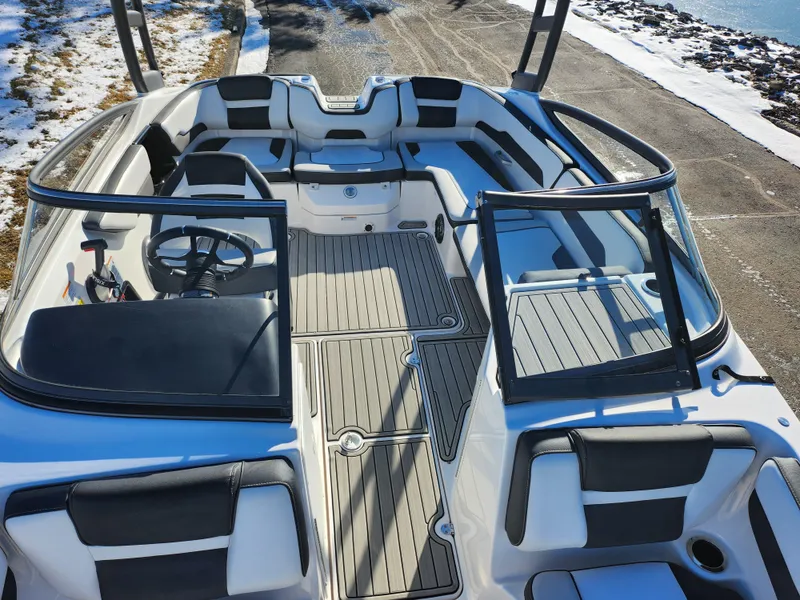 Slide: The Image of 2021 Yamaha Boats AR195 interior with seating and steering wheel, docked on a snowy day. - 18
