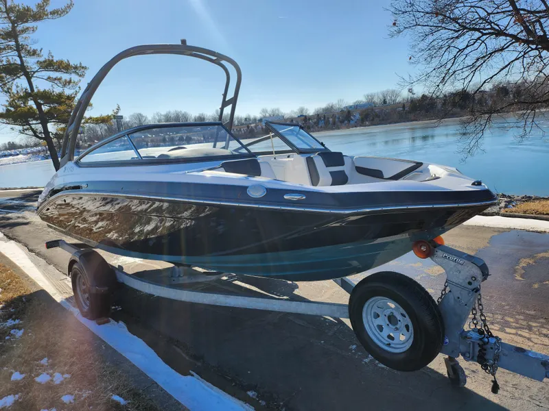Slide: The Image of 2021 Yamaha Boats AR195 on trailer by a lake, under clear blue sky. - 8