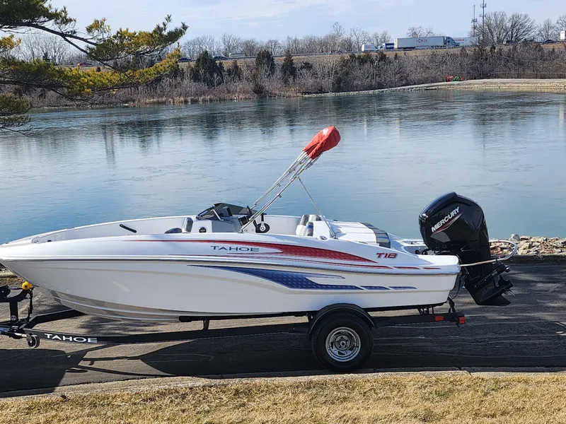 Slide: The Image of 2023 Tahoe T18 boat on trailer by a serene lake. - 10