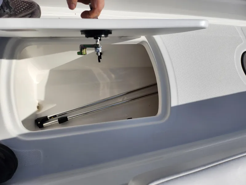 Slide: The Image of 2023 Tahoe T18 boat storage compartment with open lid and metal rods inside. - 15