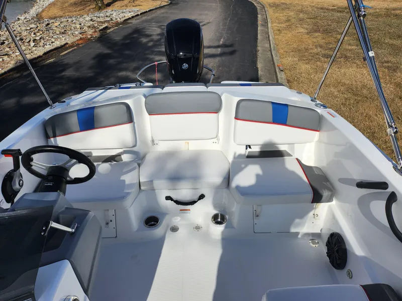 Slide: The Image of 2023 Tahoe T18 boat interior with seating and steering wheel, parked on a paved path. - 19