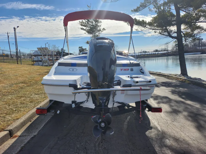 Slide: The Image of 2023 Tahoe T18 boat with outboard motor, parked near a serene lakeside. - 2