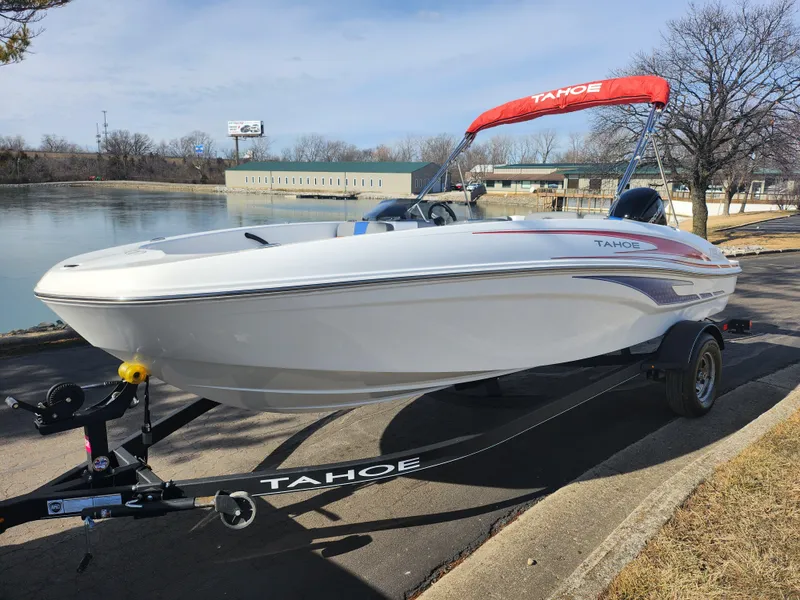Slide: The Image of 2023 Tahoe T18 boat on trailer by a lake, featuring sleek design and red canopy. - 8