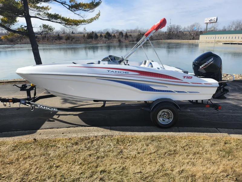 Slide: The Image of 2023 Tahoe T18 boat on trailer by a lake, featuring sleek design and vibrant graphics. - 9
