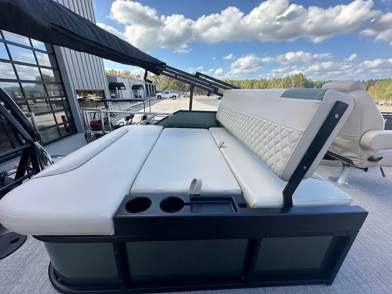 Slide: The Image of 2025 Godfrey Sweetwater 2286 SFLC boat with luxurious seating and cup holders under a blue sky. - 13