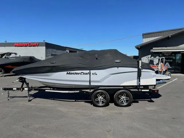Slide: The Image of 2022 MasterCraft NXT20 boat covered on trailer in dealership lot. - 20
