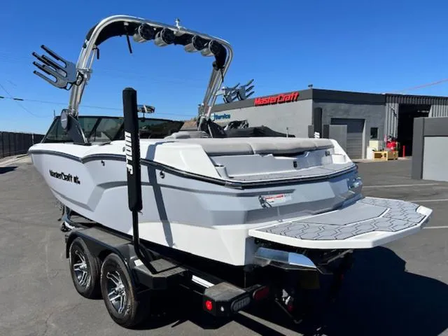 Slide: The Image of 2022 MasterCraft NXT20 boat on trailer, parked outdoors, showcasing sleek design and wakeboard tower. - 8