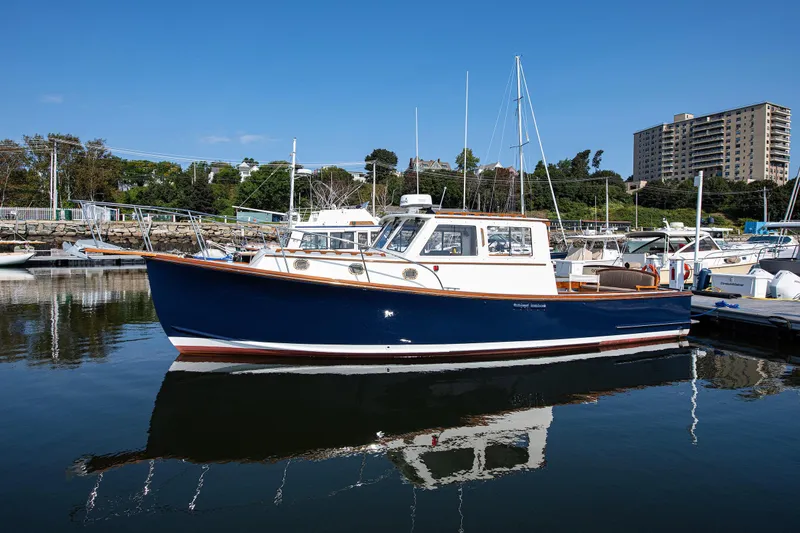 Slide: The Image of 1985 Wilbur 34 boat docked in a marina, reflecting on calm water. - 1