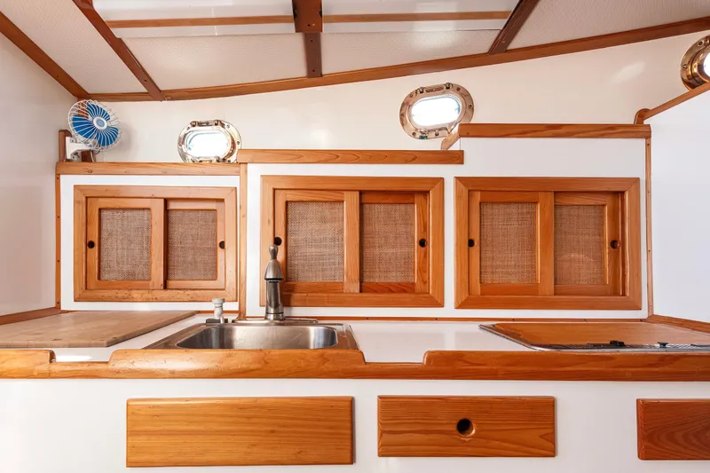 Slide: The Image of 1985 Wilbur 34 boat interior with wooden cabinets and stainless steel sink. - 13