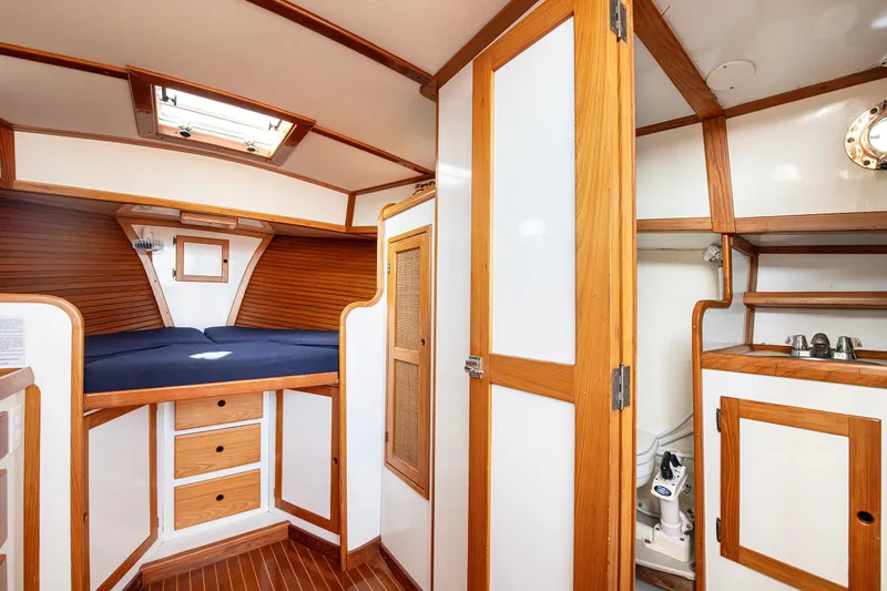 Slide: The Image of 1985 Wilbur 34 yacht interior with wood accents, cozy bed, and compact storage. - 14