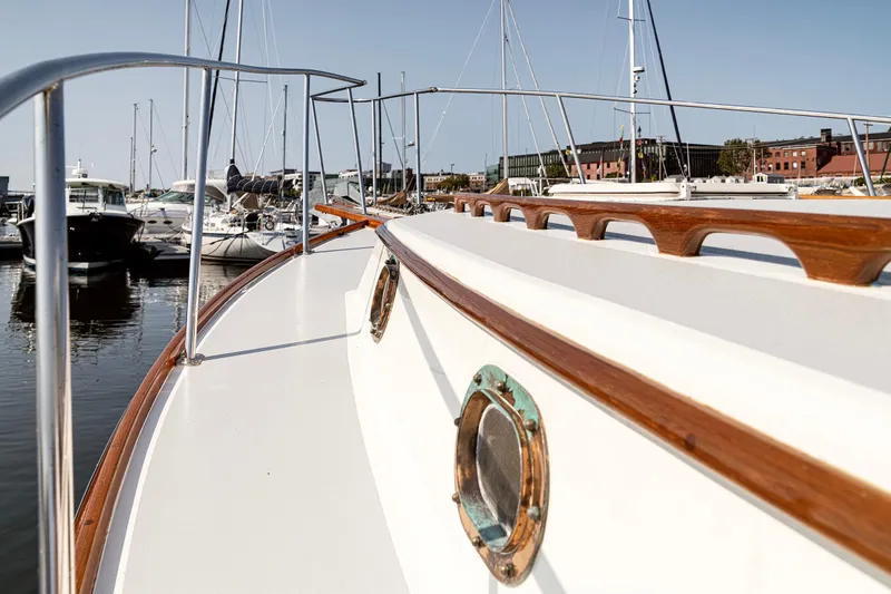 Slide: The Image of 1985 Wilbur 34 boat docked in marina, showcasing wooden details and porthole. - 18