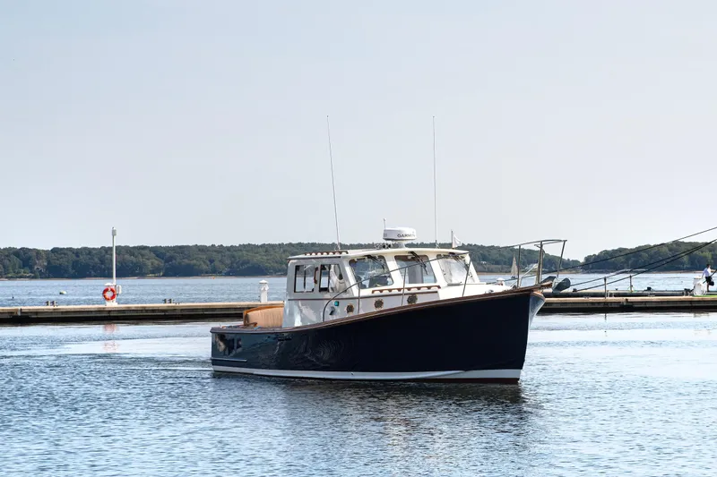 Slide: The Image of 1985 Wilbur 34 boat cruising on calm waters near a dock. - 19