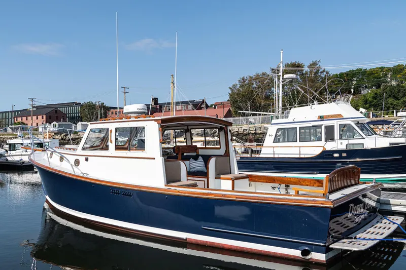 Slide: The Image of 1985 Wilbur 34 boat docked in a marina, featuring classic design and blue hull. - 22
