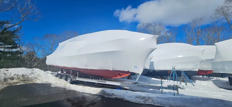 Slide: The Image of 1985 Wilbur 34 boats covered in shrink wrap, parked on trailers in snowy landscape. - 24
