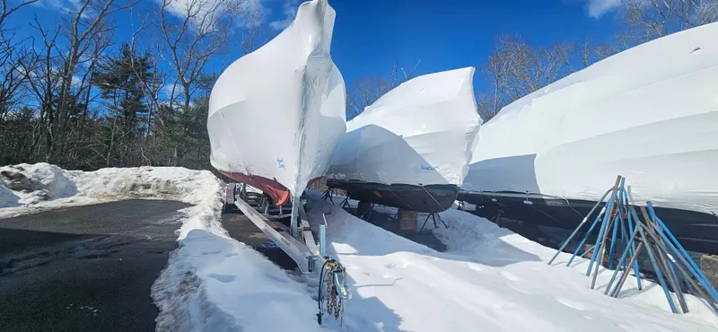 Slide: The Image of Boats covered in snow, including a 1985 Wilbur 34, stored outdoors. - 25