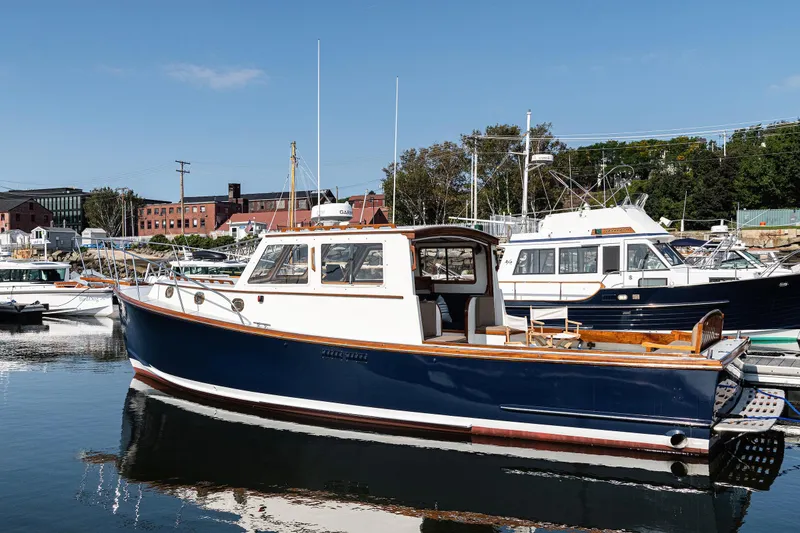 Slide: The Image of 1985 Wilbur 34 boat docked in a marina, surrounded by other vessels. - 3