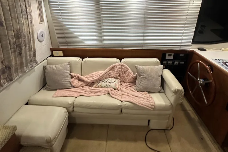 Slide: The Image of 1991 Carver 33 Aft Cabin interior with cream sofa, pink blanket, and helm station. - 18