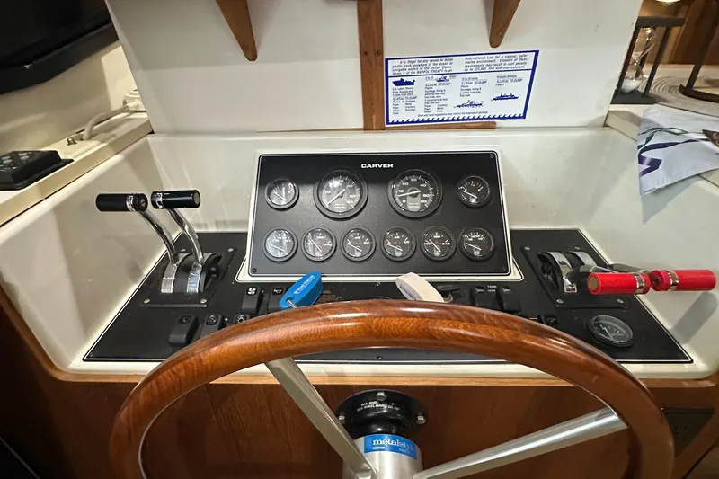 Slide: The Image of 1991 Carver 33 Aft Cabin helm with gauges, controls, and wooden steering wheel. - 21