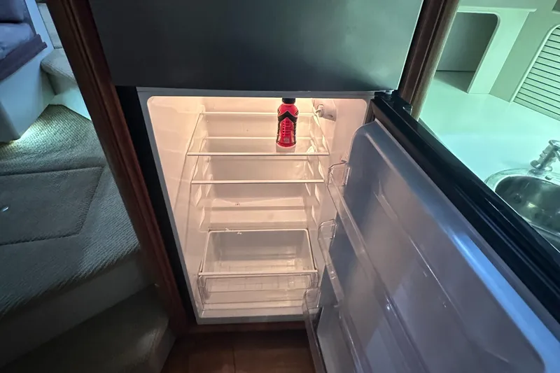 Slide: The Image of Open fridge inside 1991 Carver 33 Aft Cabin yacht, containing a single bottle. - 28